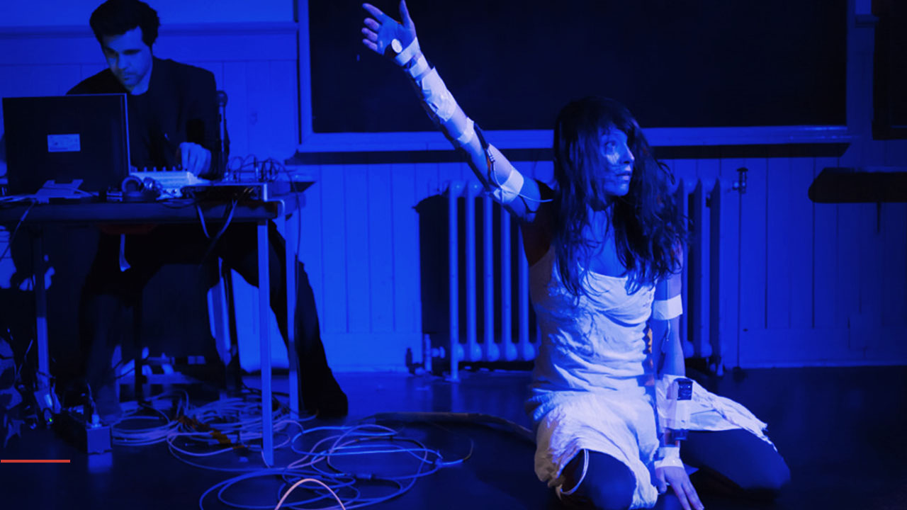 Dancer wearing cables and sensors and a person behind a desk